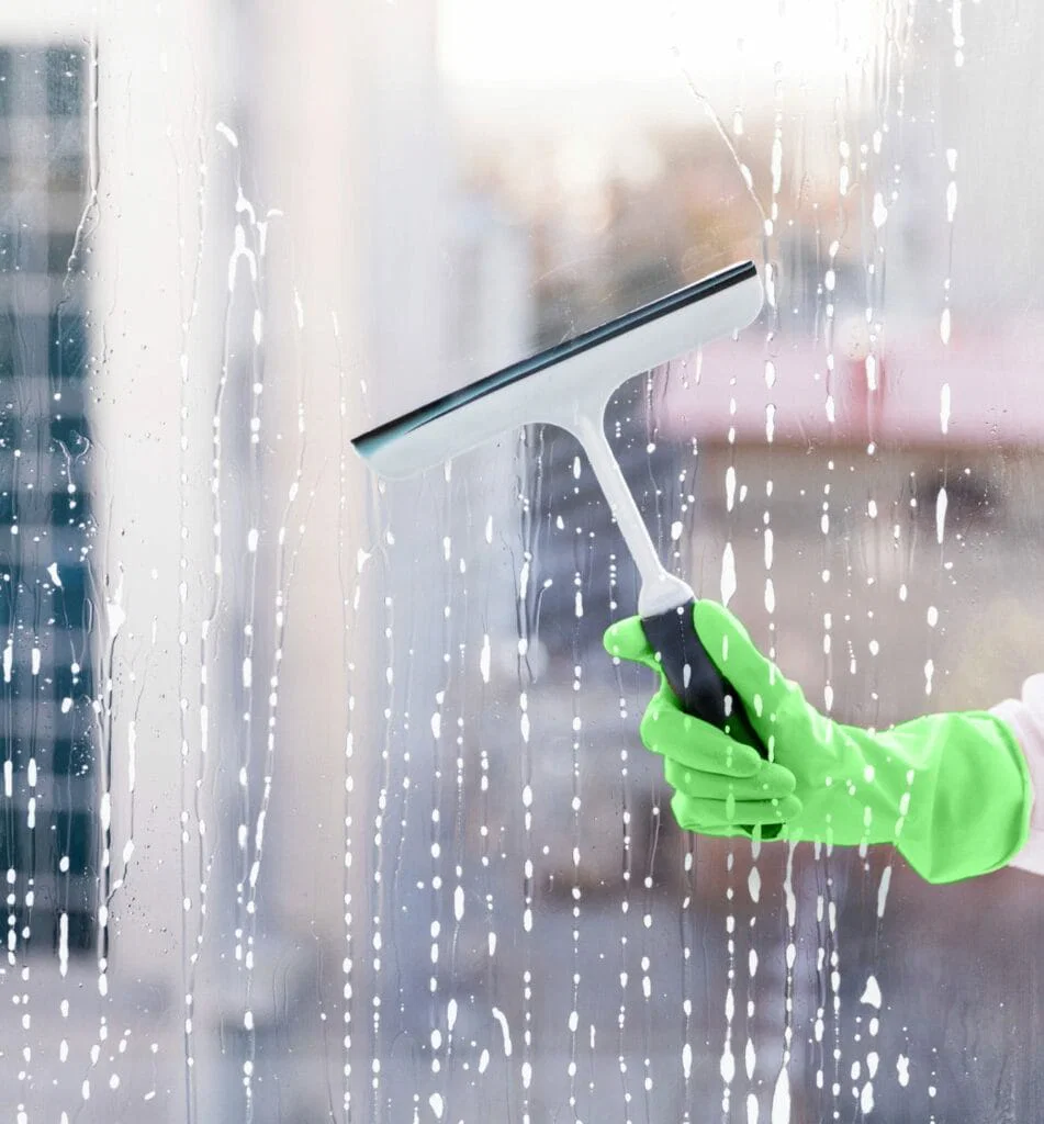 Our Services 8 Our Services A person wearing a green glove uses a squeegee to clean a soapy exterior window.